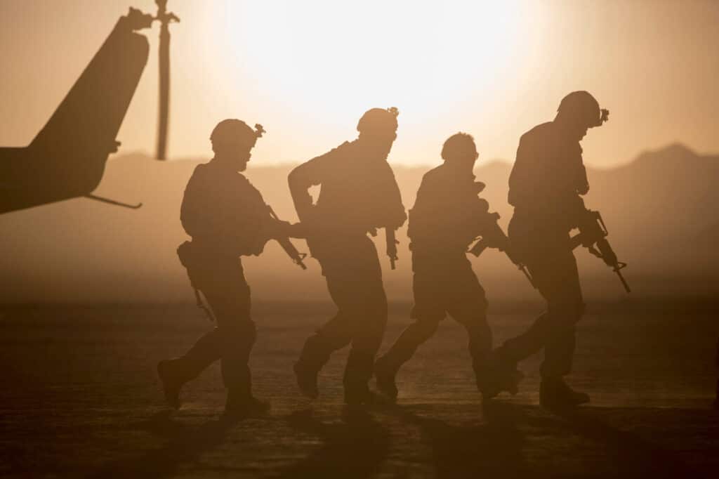 Silhouette,Of,Soldiers,Near,Helicopter,In,Desert,Landscape